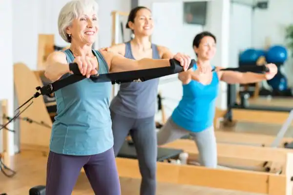Toning Arms After 60: Empowering Womens Fitness Through Effective Weight Training 2 older woman doing weight training Newport and resistance in the gym to tone upper arms