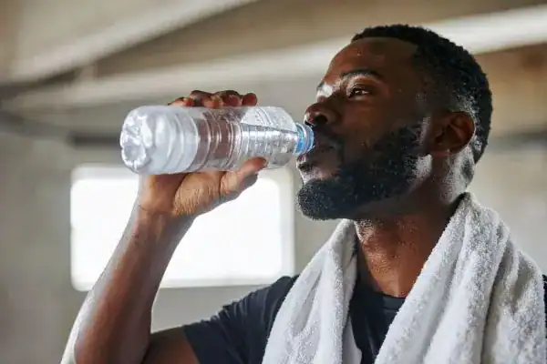 Hydration: The Secret Ingredient for a Toned Stomach and Enhanced Fitness 1 Image of man drinking water to improve hydration Newport after work out.